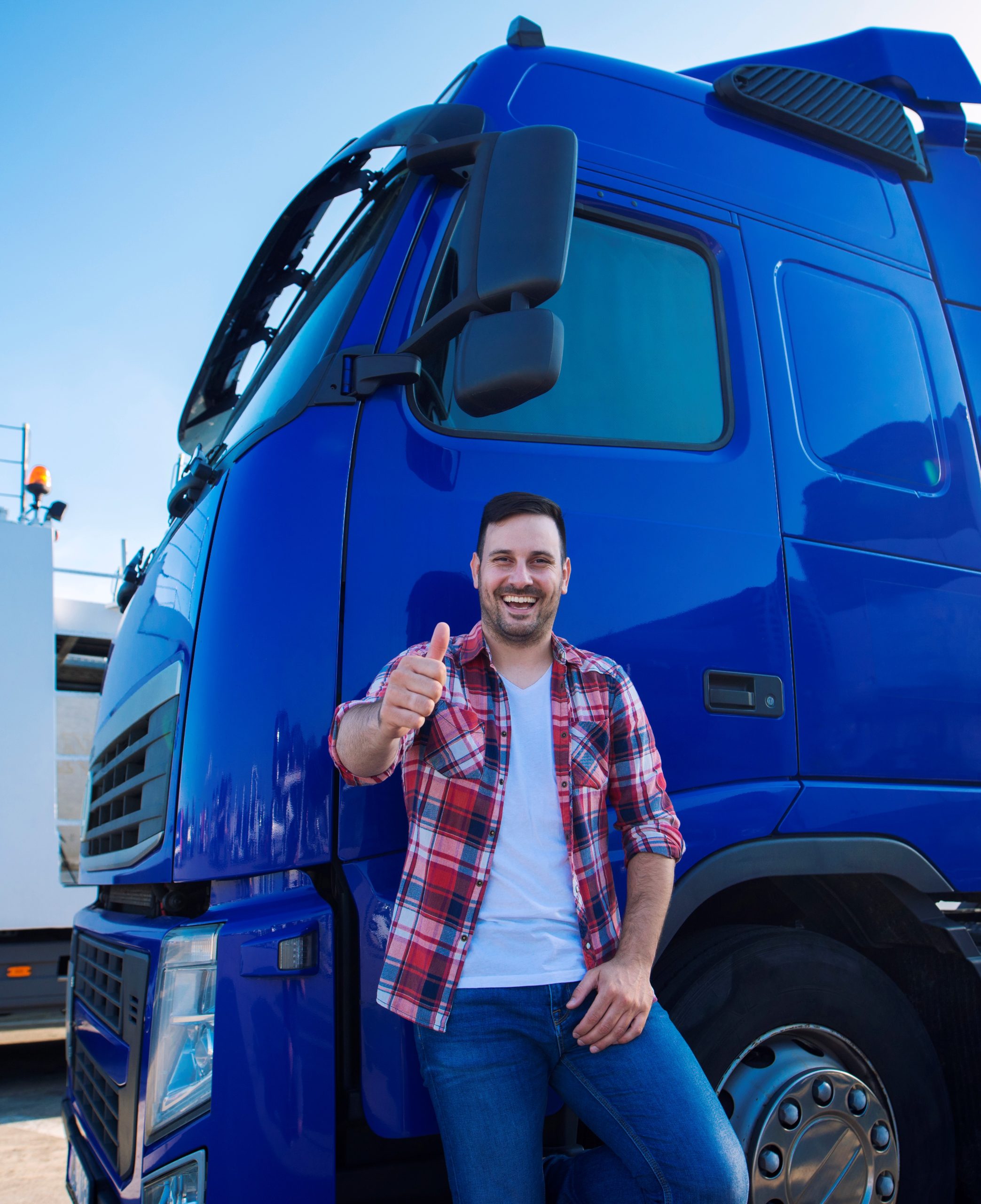 Professional truck driver in front of long transportation vehicle holding thumbs up ready for a new ride.